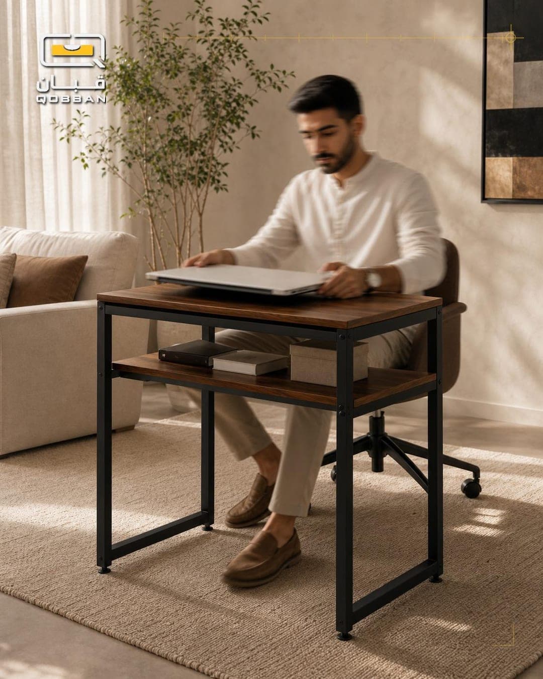 A man working on a laptop at a two-tier steel and walnut desk in a sunlit living room