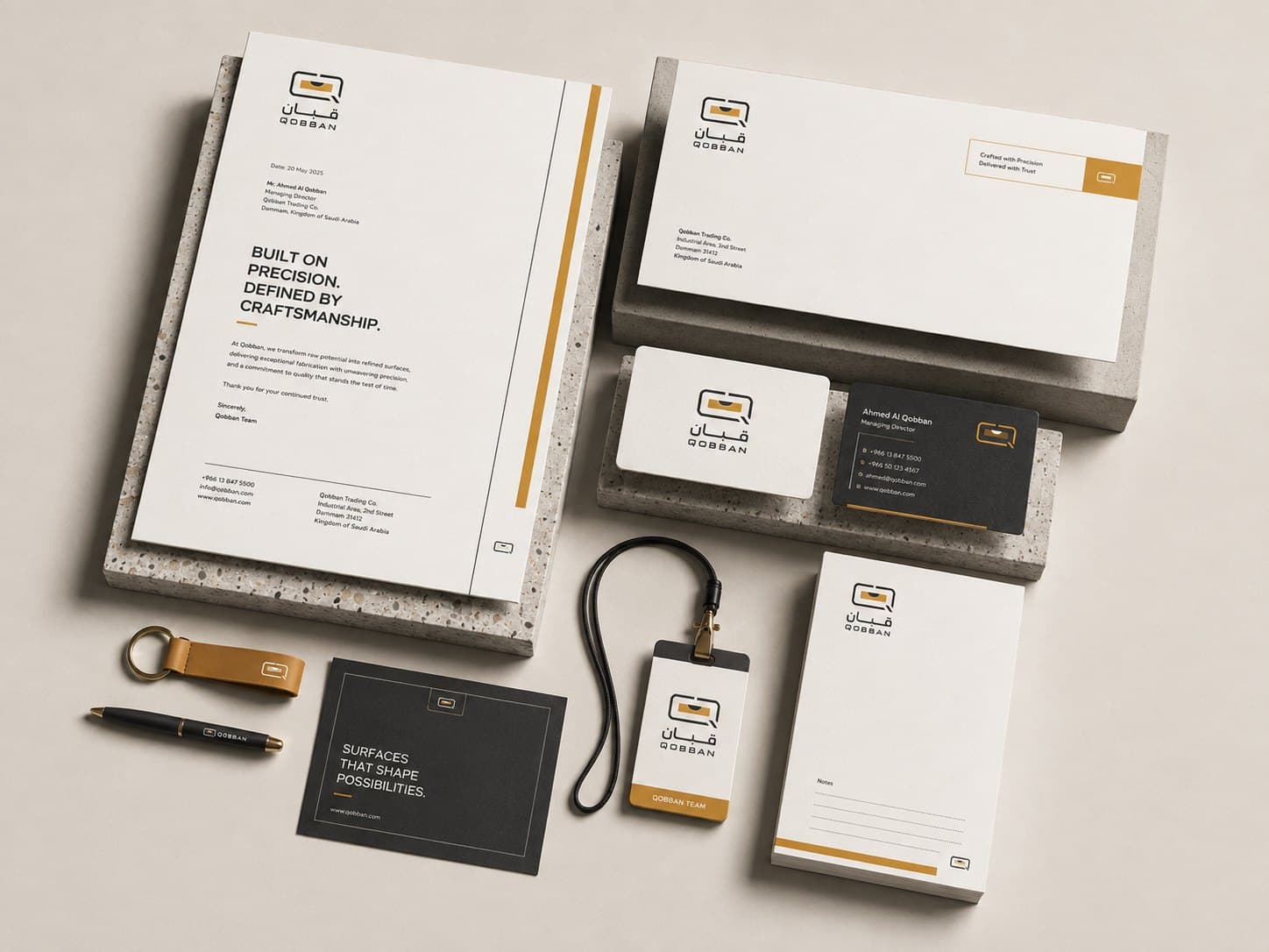 The Qobban stationery system — letterhead, envelope, business cards, notepad, lanyard and keyring in black, white and the brand gold