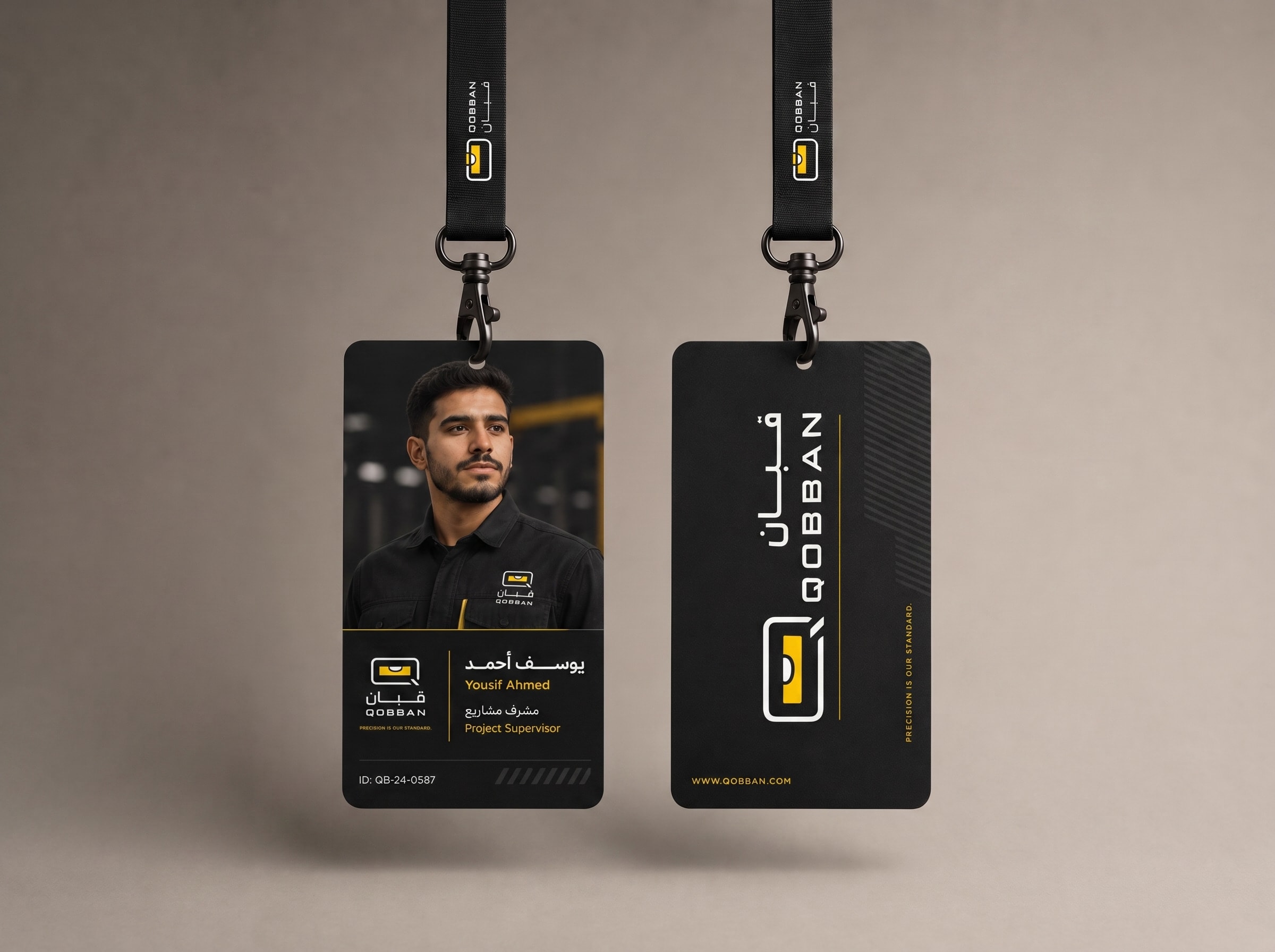 Two Qobban staff ID cards hanging on branded lanyards — a project supervisor's photo card and the reverse carrying the mark